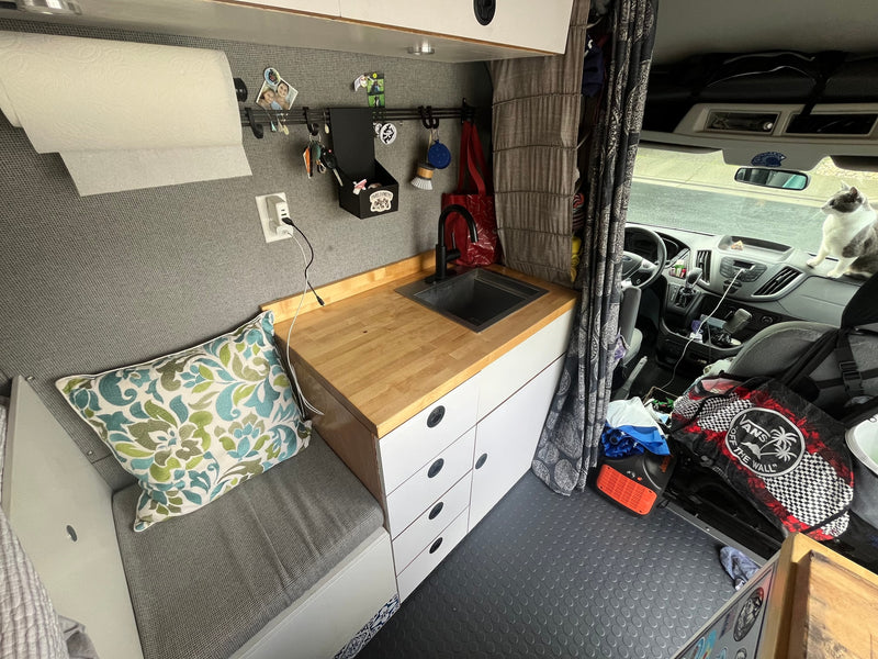 Cozy RV rental interior with compact kitchen, bench seat, and a cat on the dashboard. Ideal for van life. — photo 12