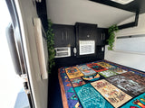 Cozy RV rental bedroom with AC, overhead storage, and a fun camping blanket for adventures.