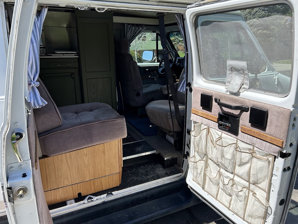  and fun artwork. Ready for your journey.|Cozy RV rental interior showcasing a comfortable bed with striped bedding — photo 8