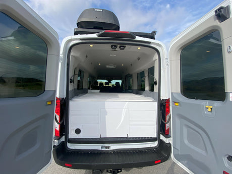 RV rental camper van. Rear doors open revealing custom interior, storage/bed unit, and Thule roof box.