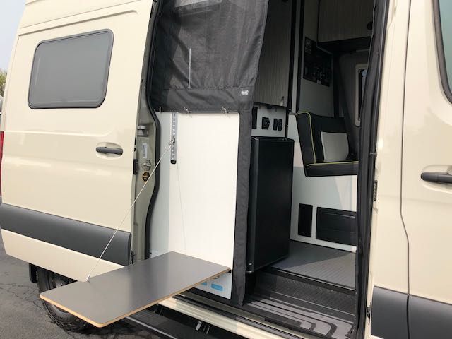  and an outdoor pull-out table.|Open side of an RV rental van revealing compact interior — photo 3