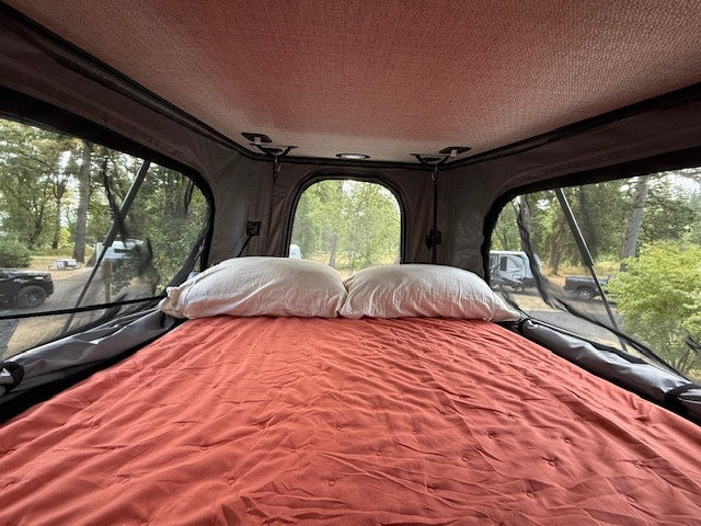 Pop-top interior: cozy double-size bed with quilt, blanket, and sheets - and large windows open with mesh for bug screens or zipped closed privacy and darkness.