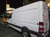 White Mercedes-Benz Sprinter van, likely an RV rental or camper conversion, with a Furrion roof unit, parked at night.