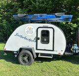 This white teardrop camper from Joy Ride RV Rental, named Bushwhacker, is ready for outdoor adventures with a kayak on top.