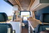 Step inside this custom camper van RV rental, featuring a modern kitchen, dining area, and scenic views out the back.