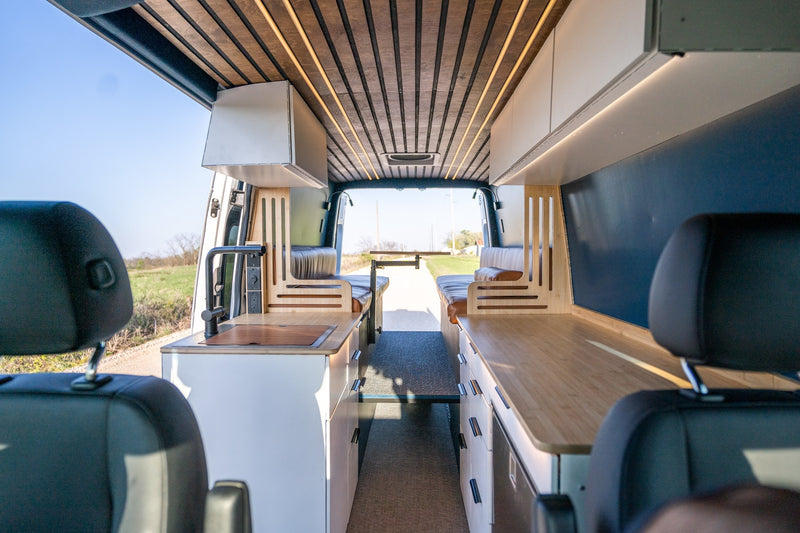 Step inside this custom camper van RV rental, featuring a modern kitchen, dining area, and scenic views out the back. — photo 1