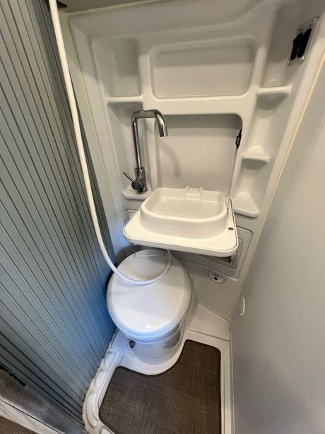 This RV rental's compact bathroom includes a toilet, fold-down sink/faucet, and shower hose for efficiency.