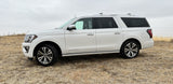 Looking for an rv rental? Consider this spacious white Ford Expedition Platinum SUV parked in a dry, rural field.