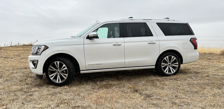 Looking for an rv rental? Consider this spacious white Ford Expedition Platinum SUV parked in a dry, rural field.