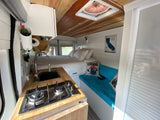 Inside a cozy RV rental: compact kitchen, comfortable bed, and living space. Perfect for adventure.
