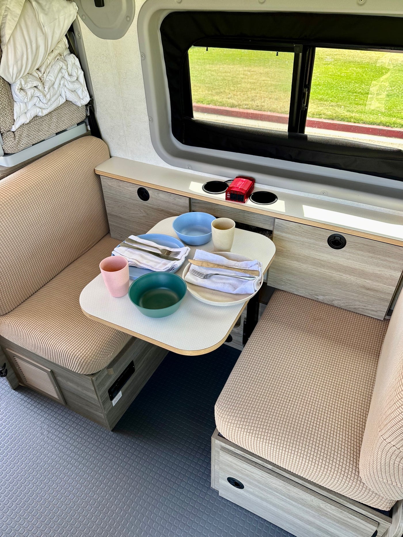 Modern rv rental interior showing a dining nook with set table, benches, and ample storage. Perfect for travel! — photo 4
