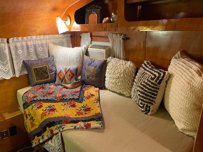 Experience a comfortable RV rental interior: soft pillows, a colorful blanket, and an AC unit for a cozy stay.