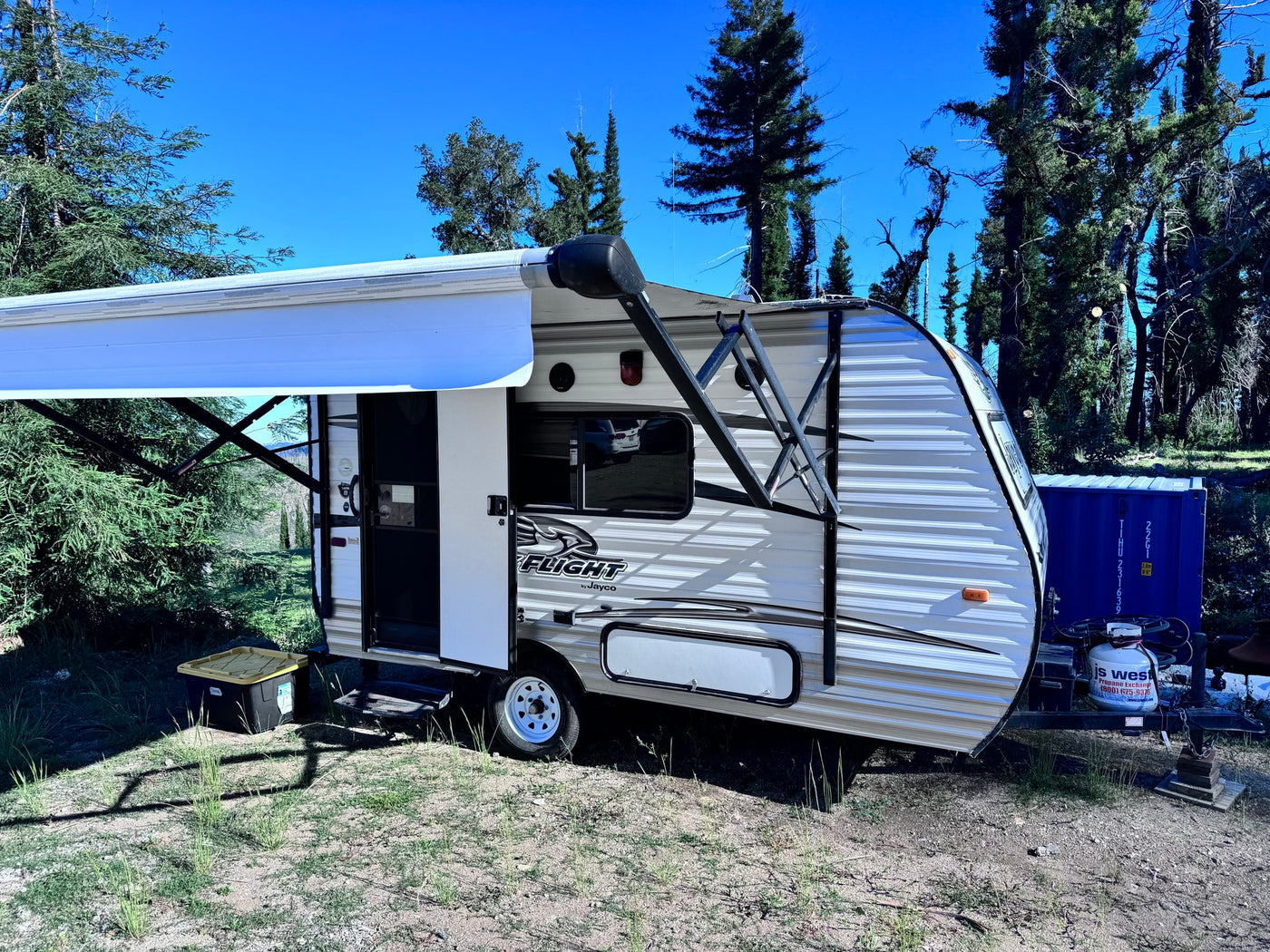 A white Jayco Flight travel trailer RV rental with an extended awning, parked in a sunny outdoor setting with trees. — photo 2