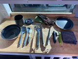 Essential kitchen gear for your RV rental: pots, pan, spatulas, gloves, plate, and towel laid out on a wooden counter.