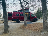 Red Winnebago Solis camper van rv rental with pop-top open at a scenic campsite. Ready for adventure and van life.