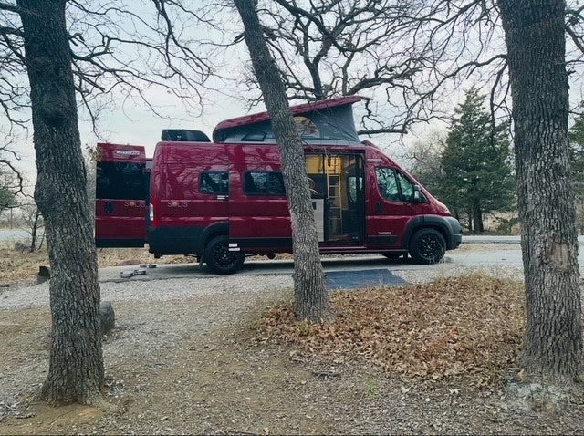 Red Winnebago Solis camper van rv rental with pop-top open at a scenic campsite. Ready for adventure and van life. — photo 3
