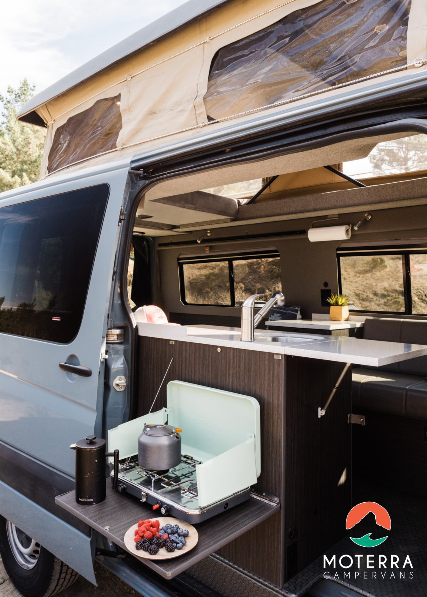  stocked RV rental fridge filled with fresh food and drinks for your journey.|A couple and their dog relax inside a comfortable RV rental. Experience cozy van life adventures.|Efficient RV rental storage: pull-out drawers with kitchenware (mugs