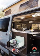  stocked RV rental fridge filled with fresh food and drinks for your journey.|A couple and their dog relax inside a comfortable RV rental. Experience cozy van life adventures.|Efficient RV rental storage: pull-out drawers with kitchenware (mugs