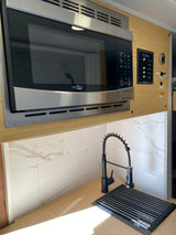 Modern RV rental kitchen featuring a High Pointe microwave, black pre-rinse faucet, and Paneltronics control panel.
