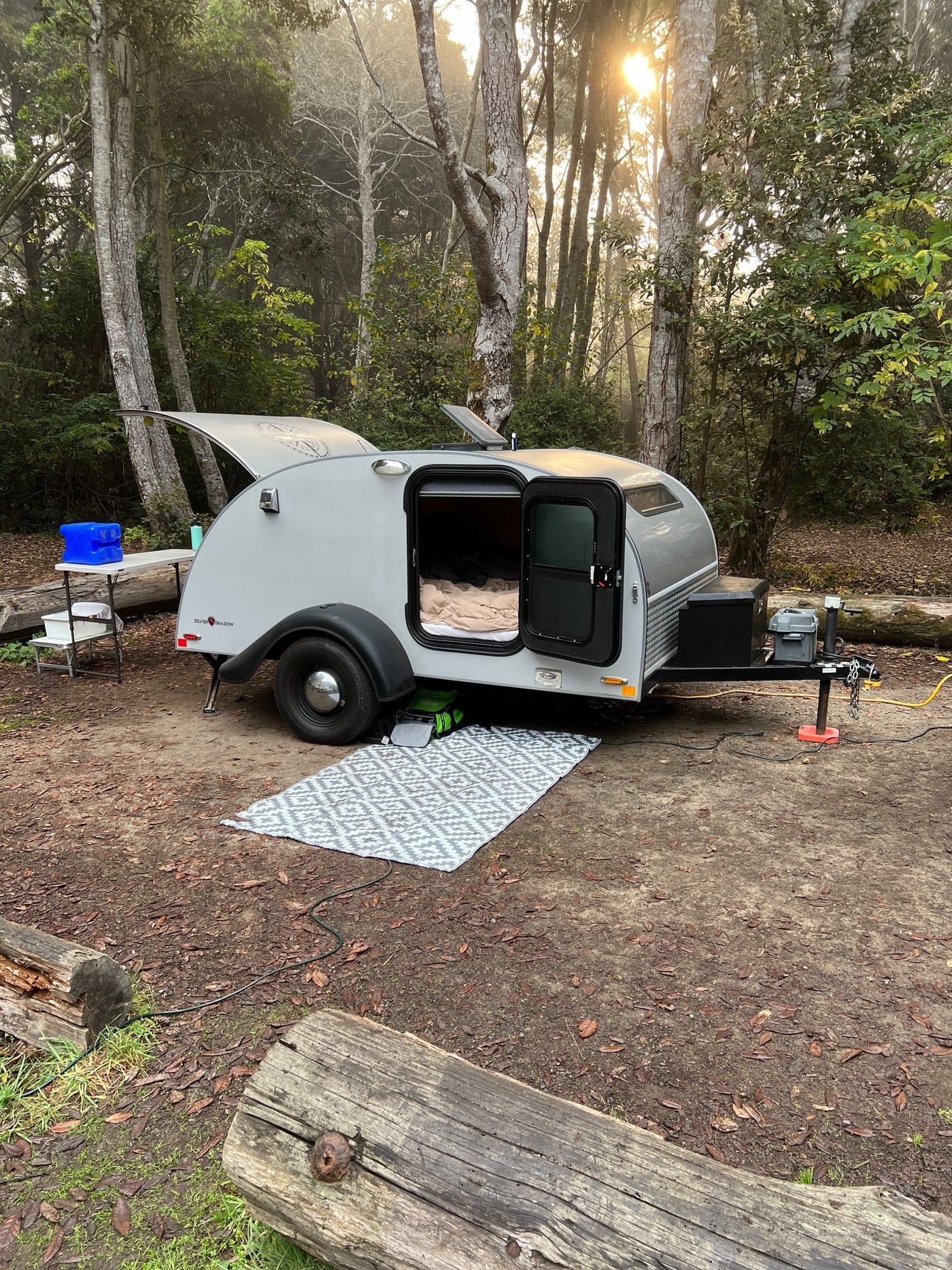  with a cozy bed visible inside.|Scenic RV rental trip! A teardrop camper by a golden autumn vineyard — photo 2