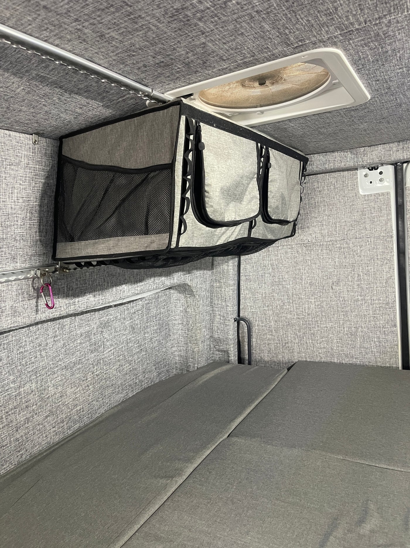  parked outdoors by a red storage container.|This white RV rental camper van features a rooftop awning — photo 3