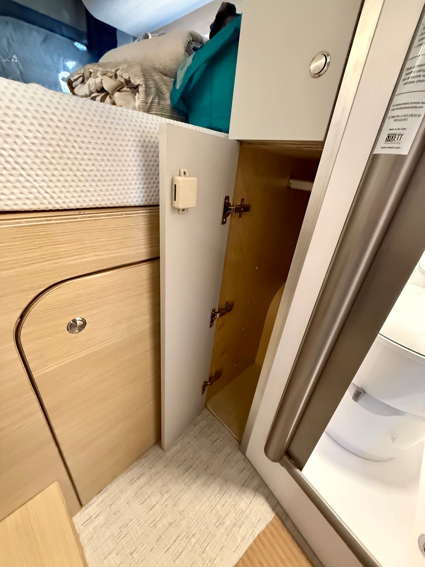 Inside an RV rental: light wood cabinets, cozy bed, and clever storage solutions. A peek into the compact bathroom.