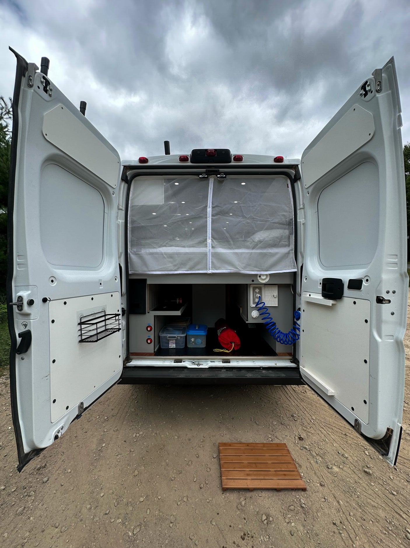 Ready for adventure! This rv rental's open back reveals custom storage, an outdoor shower, and a privacy curtain.