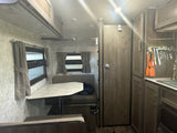 RV rental interior: dinette, kitchen with sink & utensils, and bathroom door in a compact camper layout.