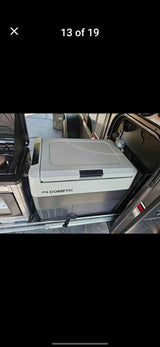 An RV rental's slide-out outdoor kitchen with a Dometic portable fridge/freezer and stove, ready for camping adventures.
