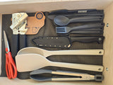 RV rental kitchen drawer with camping gear: Sea to Summit cutlery, cooking tools, knife, can opener on non-slip mat.
