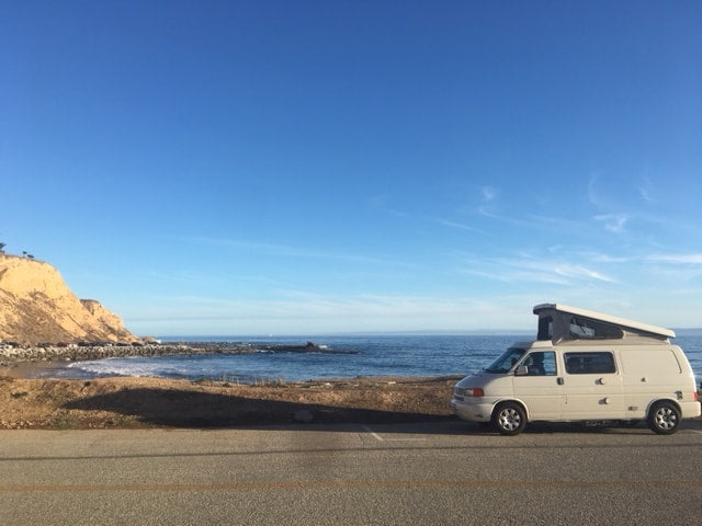 A light-colored camper van with its pop-top raised