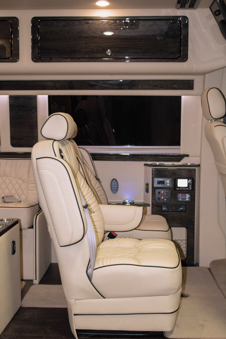 Luxury RV rental interior with cream leather captain chairs, TV, and comfort controls for premium travel.