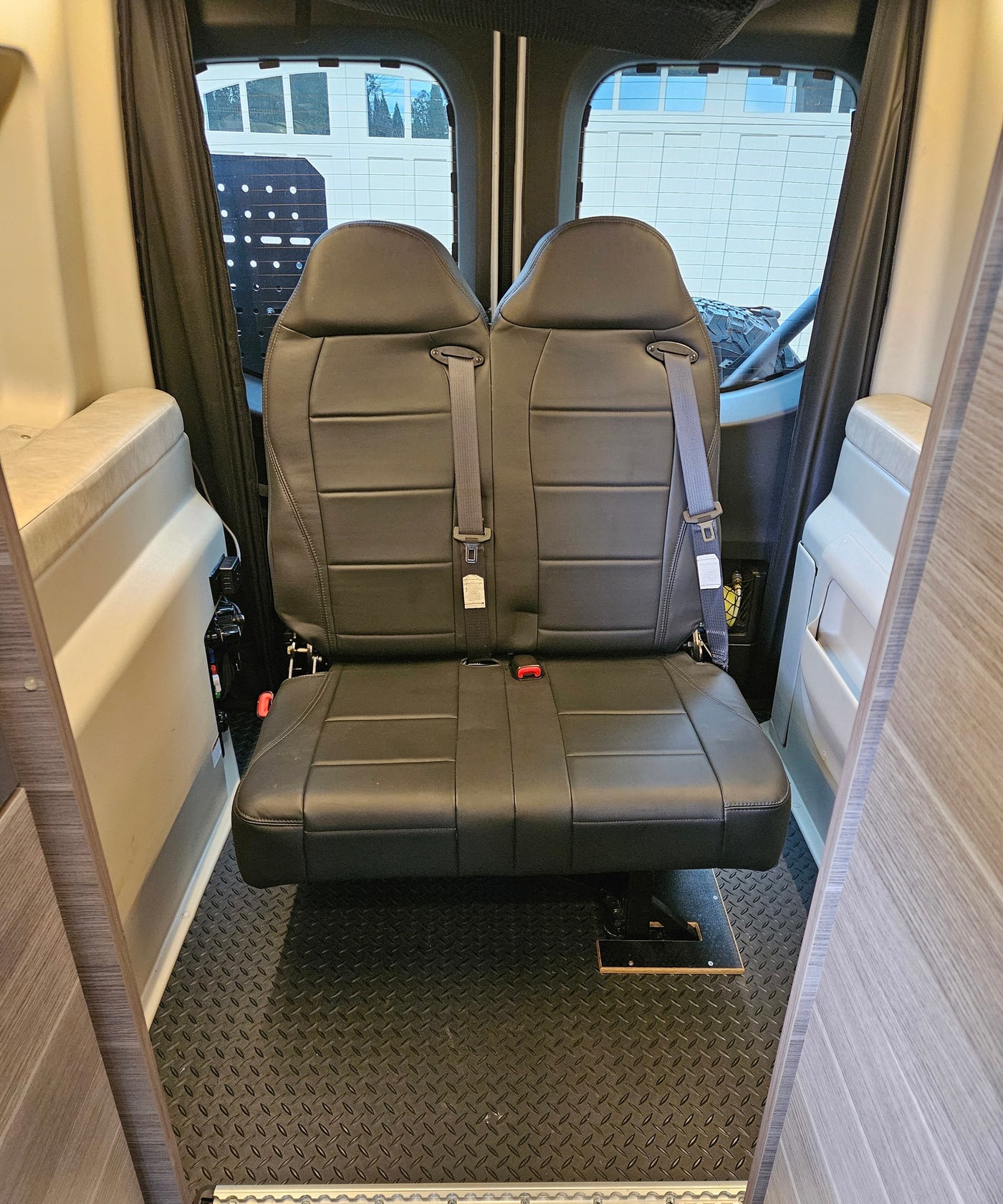 RV rental: View of two black passenger seats with seatbelts and textured diamond-plate floor for passenger safety. — photo 5