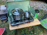 Perfect for your RV rental adventure: Camping stove, pots, and portable fridge on a table for outdoor cooking.