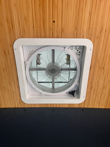 A white Maxxfan ceiling vent installed in an RV rental, set against warm bamboo paneling.
