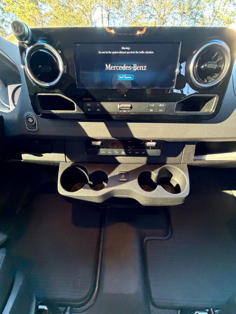 Inside an RV rental: Mercedes-Benz Sprinter dashboard with infotainment, climate controls, and cupholders.