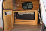 Inside an RV rental: a custom wood interior with a Dometic fridge, power outlets, and a cozy built-in setup.