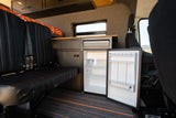 Inside this RV rental: a modern camper van with a comfy bench seat, custom kitchenette, and an open refrigerator.