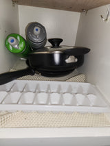 Water bottles, pot, pan, and ice tray neatly stored in an RV rental cabinet on a non-slip mat.