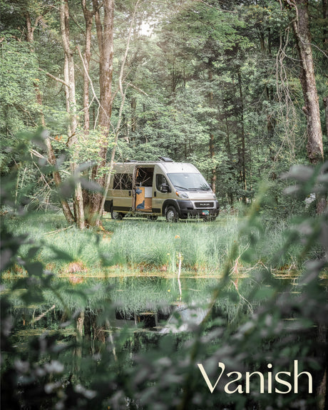 Explore nature with this tan camper van rv rental parked by a reflective pond in a tranquil forest.