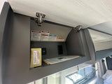 RV rental: An open overhead cabinet with safety warnings, a cribbage set, and a USB charging port.