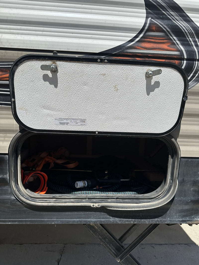 An open RV rental storage compartment reveals a hose and straps, ready for your adventure gear. — photo 11