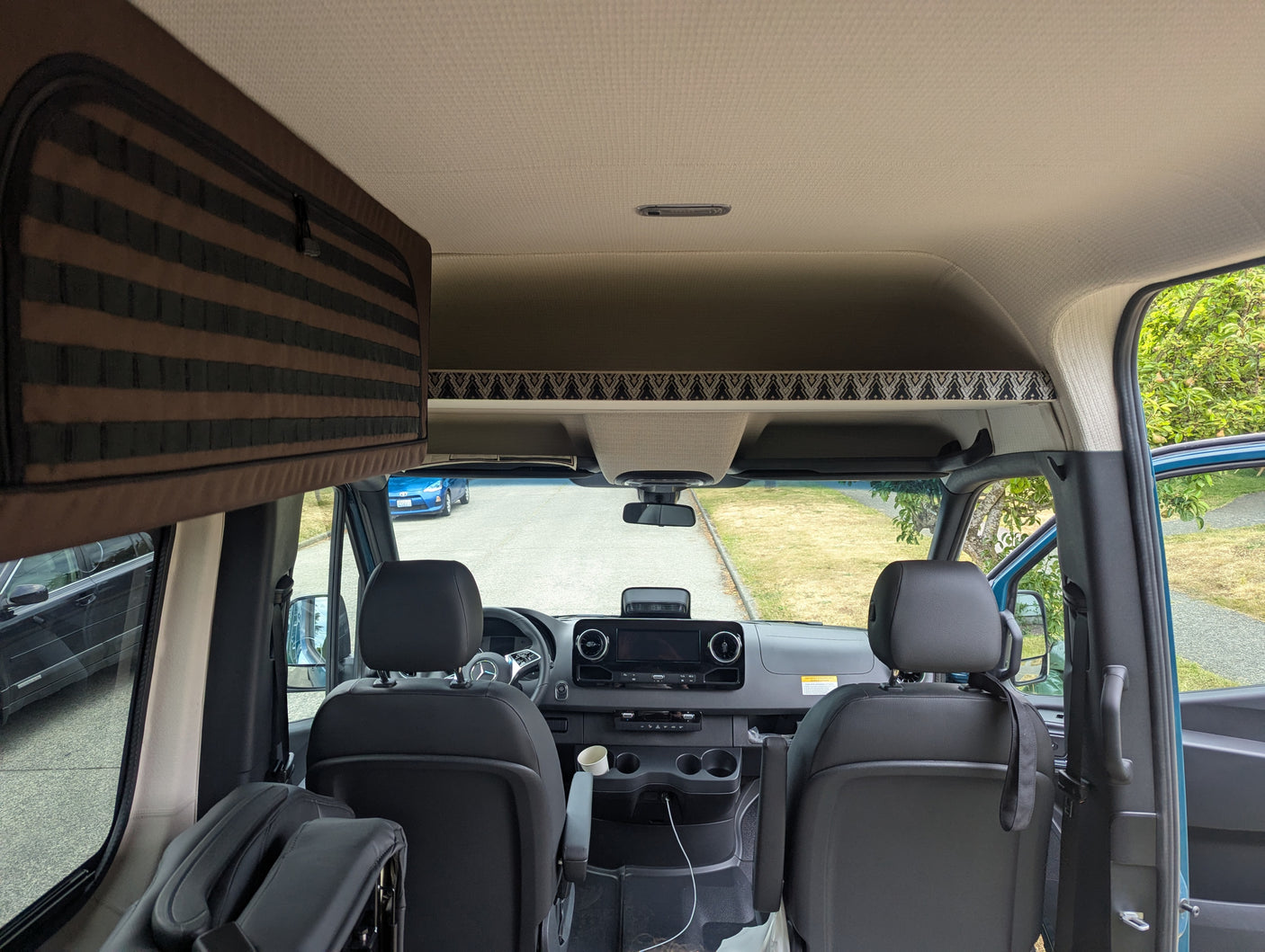 RV rental interior: View from the back into the spacious front cabin with dashboard, seats, and overhead storage.