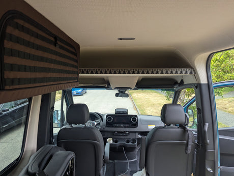 RV rental interior: View from the back into the spacious front cabin with dashboard, seats, and overhead storage.