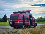 Maroon Winnebago Solis camper van (RV rental) parked on a roadside with its pop-top extended.