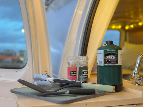 RV rental kitchen shows a Bluefire propane tank, Trader Joe's salt and pepper, and utensils, perfect for camping meals.