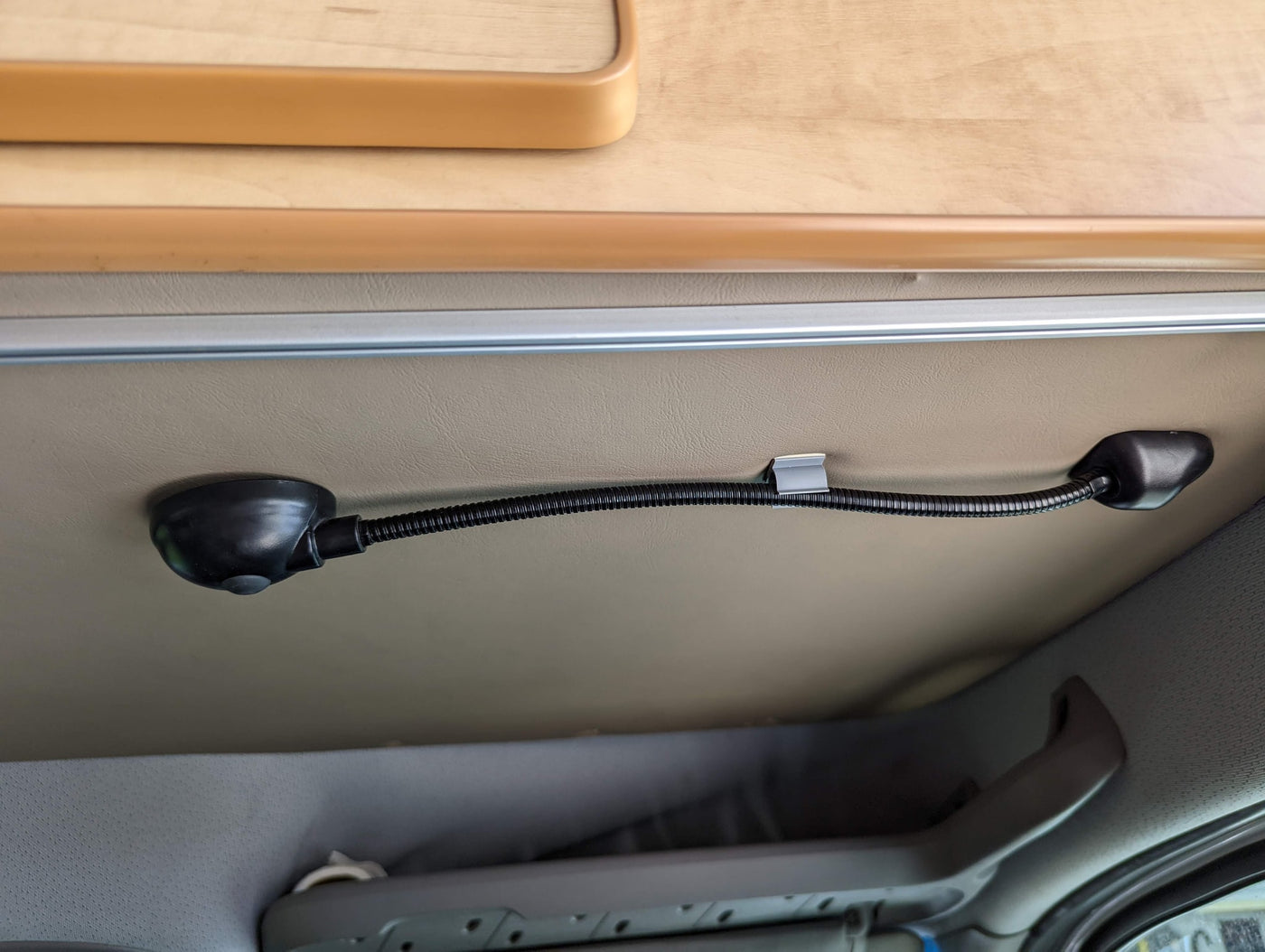 An RV rental interior, featuring an overhead wooden cabinet and a flexible gooseneck LED reading light on the ceiling. — photo 14