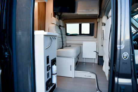 RV rental's inviting interior: features comfortable seating, a fold-out table, and essential controls, including a fire extinguisher.