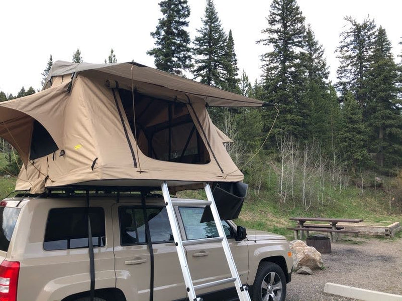  offering a unique RV rental outdoor adventure.|SUV with a rooftop tent deployed at a campsite among pine trees — photo 2