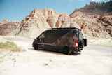 Adventure-ready rv rental: A custom geometric-patterned camper van is parked on a sandy shoulder amidst majestic Badlands peaks.